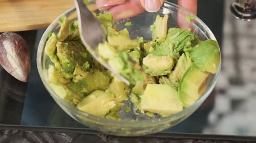 Preparing Avocado Mash in Glass Bowl with Fork