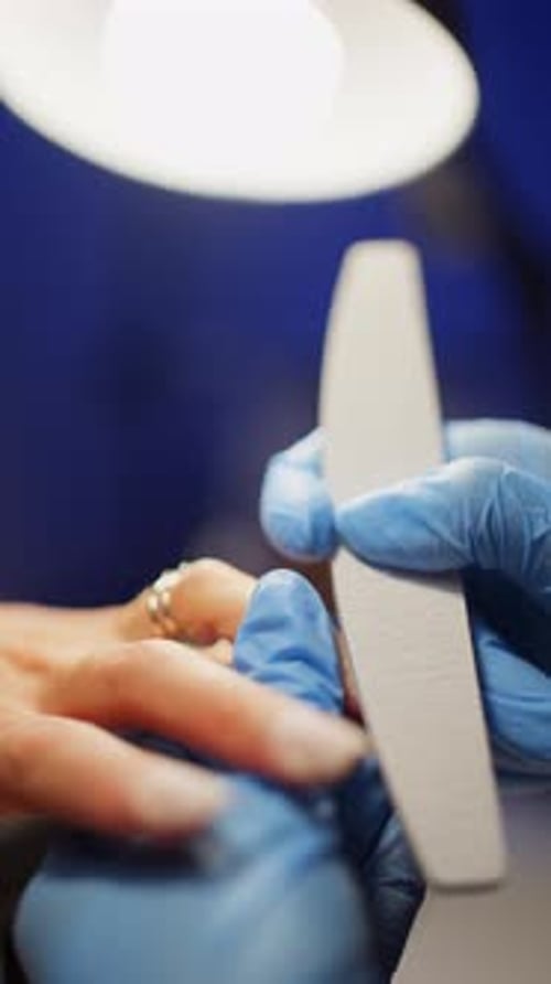 Manicurist Filing Client's Nails in Beauty Salon