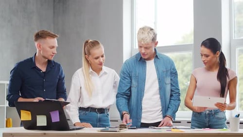 Team of Young Startupers is Working at the Table in the Office Discussing the Strategy and
