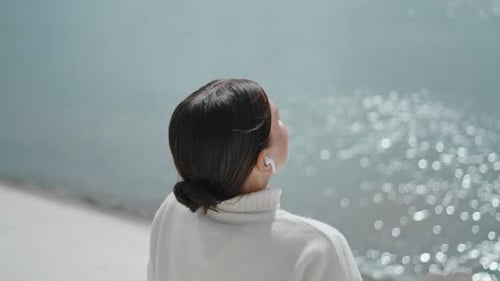 Young Woman Speaking by Wireless Earphones Sitting at Waterfront Sunny Weekend Close