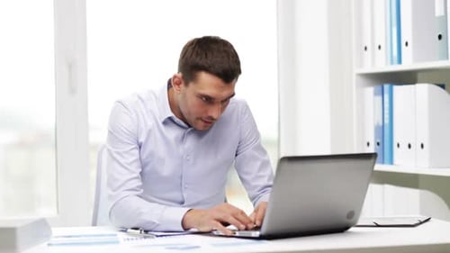 Busy businessman working with laptop and paperwork in the office