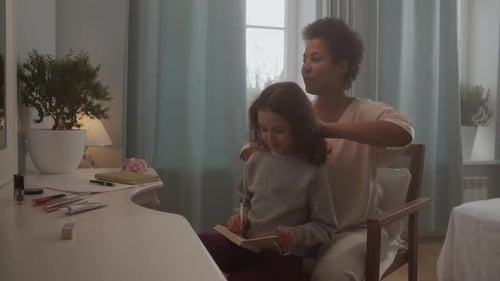 Woman Brushing Girl's Hair at Vanity Indoors