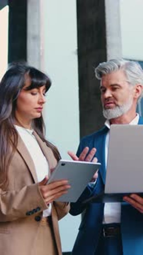 Two Business Partners a Man and a Woman in Formal Attire are Standing Outside a Modern Office