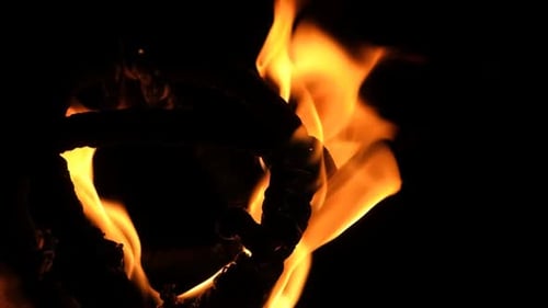 Extreme close-up of a fireball burning against a dark background, torch used in fire performances.