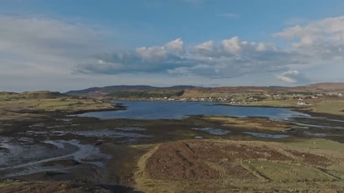Cinematic aerial drone flight over a vast cracked dried lake bed on a hot sunny day with a small