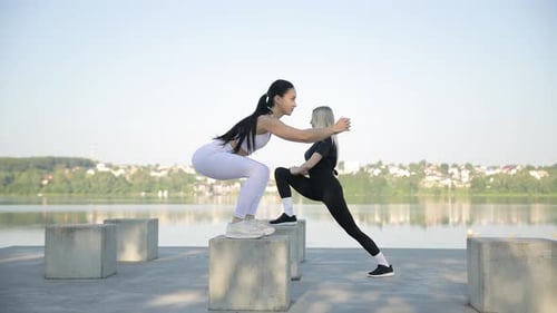 Sporty Women in Sportswear Doing Exercises Outdoors Near the Lake