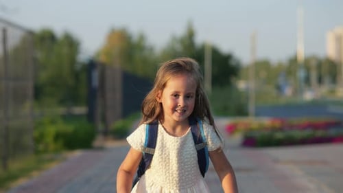 Aufgeregtes Mädchen mit Schultasche rennt zur Schule vorbei am Sportplatz
