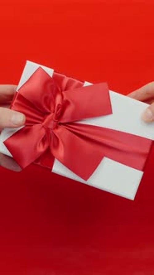 White Gift with Red Bow on Red Background