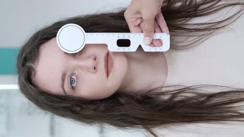 Attentive optometrist examining a beautiful female patient, testing her vision using a ruler to dete