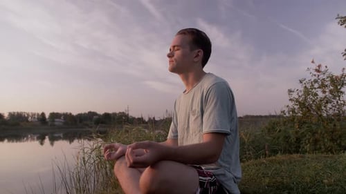 Young Adult Meditating by a Peaceful Lake