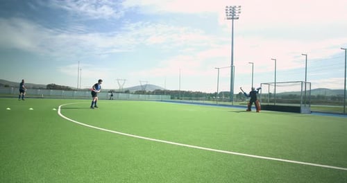Playing field hockey, male players practicing on outdoor turf field
