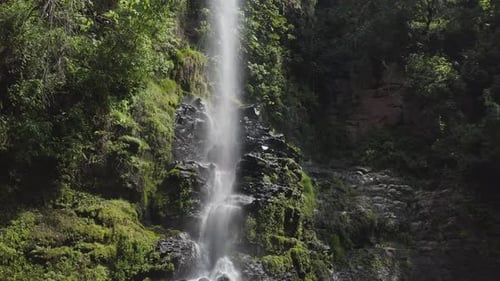 Tropical Waterfall Cascading Down Mossy Rocks