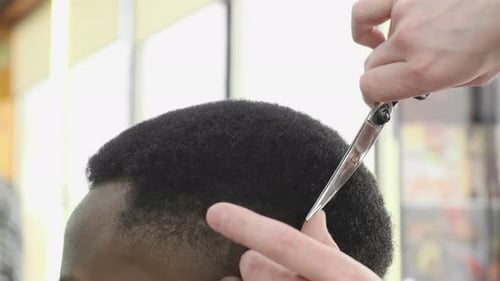 Barber Trimming Black Hair with Scissors in Salon