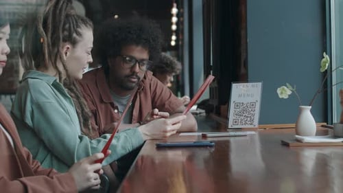 Three Friends Looking Through Menu Sitting at Counter in Restaurant