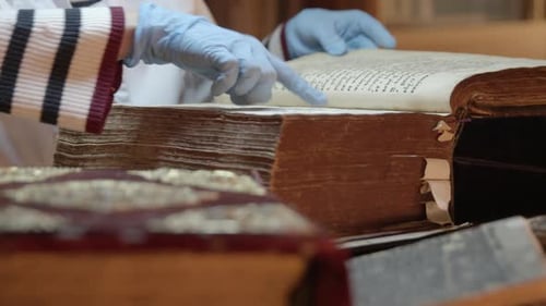 Gloved Hands Examining Ancient Manuscript in Library