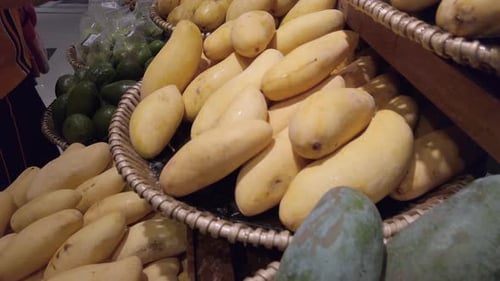 Panning camera over the fruit shelf stall in supermarket with many kind of mangoes on stall