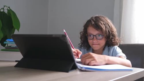 Little Adorable School Boy with Eyeglasses Studying Online From Home Kid Using Digital Tablet