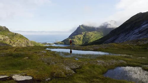 Attractive Woman in Trekking Clothes with Stands on Top of a Mountain Range and Looks Around High in