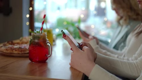 Anonymous Women Texting Via Smartphones in Cafeteria