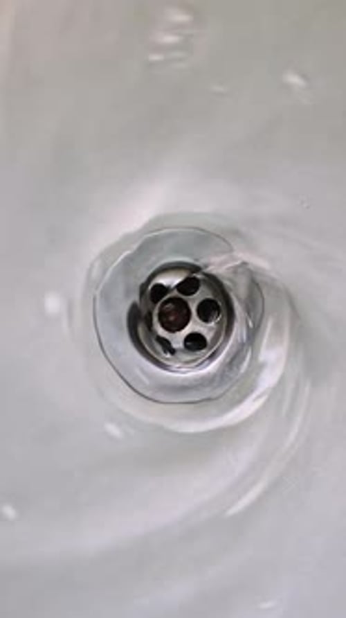 Water Swirling Down the Drain Hole of a Stainless Steel Sink Close Up Vertical Video