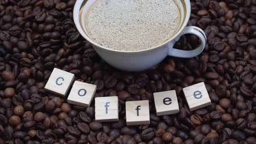 Cup of Coffee surrounded by Coffee Beans