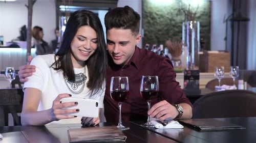 Couple Look at Smartphone at the Restaurant
