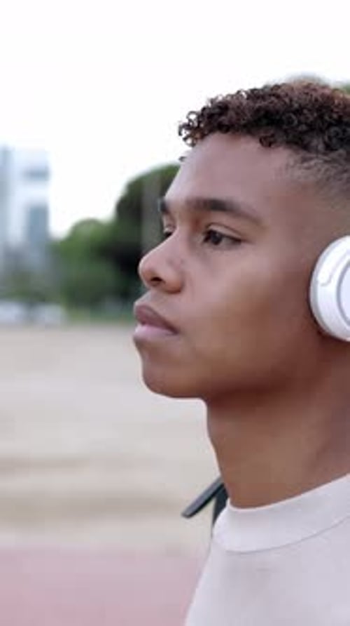 Adolescente latino hispânico caminhando ao ar livre enquanto ouve música