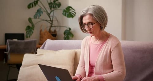 Senior Woman Using Laptop on Sofa at Home