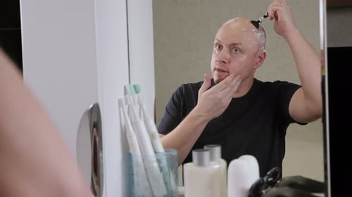 Man Shaves His Head in Bathroom Mirror