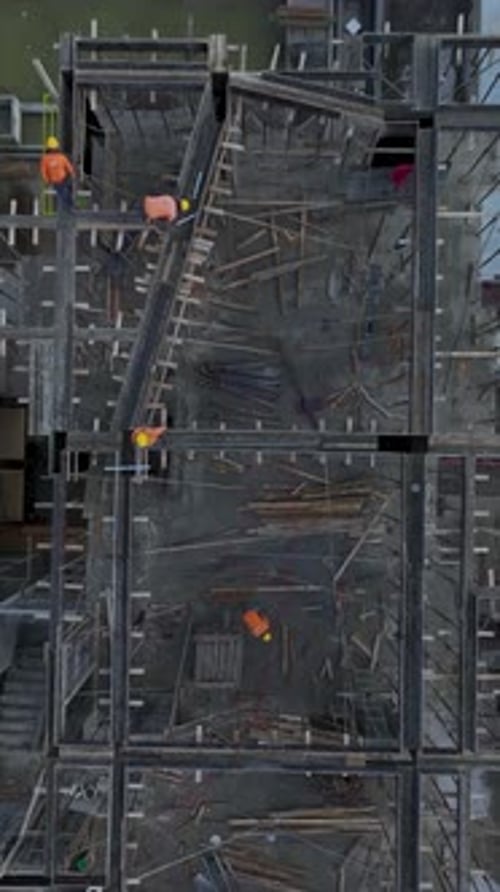 Vertical Video Aerial Perspective of Construction Workers Performing Varied Tasks With Equipment on