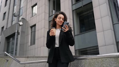 Happy Businesswoman Standing Near Office Building Drinking Coffee From Disposable Paper Cup