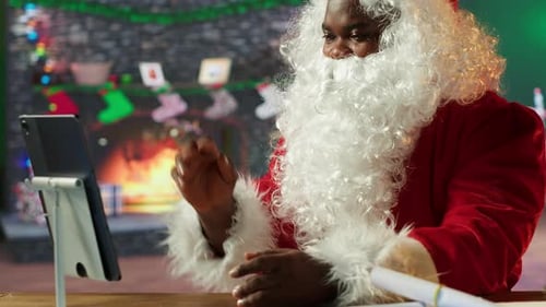 Father Christmas Checking Online Gift Lists on a Tablet in Cozy Festive Workshop