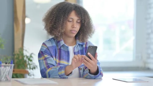 Woman Using Mobile Phone at Desk Indoors