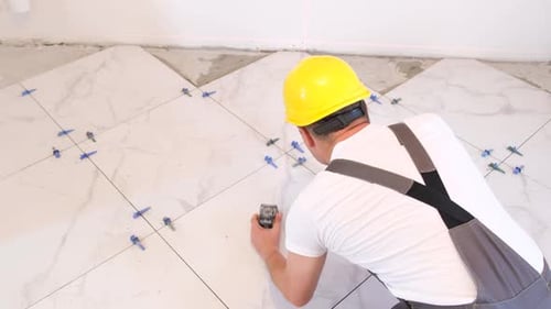 Construction Worker Placing Tile Using Leveling Tool