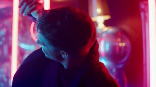Closeup Happy Guy Enjoying Music On Neon Lights Background. Portrait Of Attractive Male Person Da...