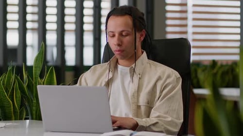 Young Adult Works on Laptop in Modern Office