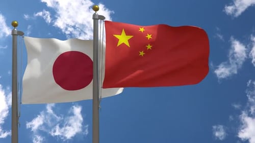 Japan and China National Flags Waving in Blue Sky