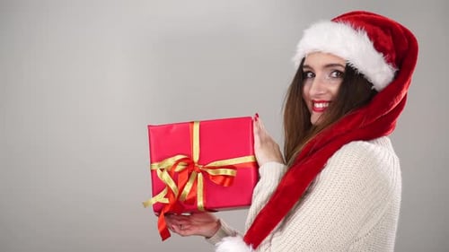Woman in Santa Hat Holding a Christmas Gift