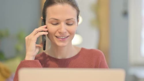 Close Up of Beautiful Woman Talking on Phone while using Laptop
