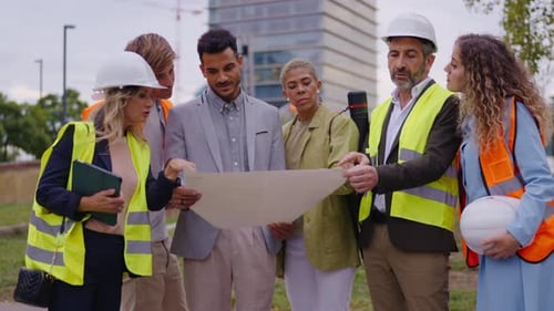 Construction Team Reviewing Blueprints at Building Site
