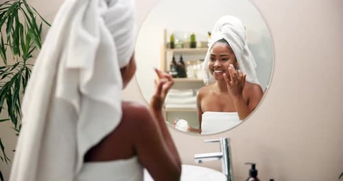Woman Applying Face Cream in Bathroom Mirror