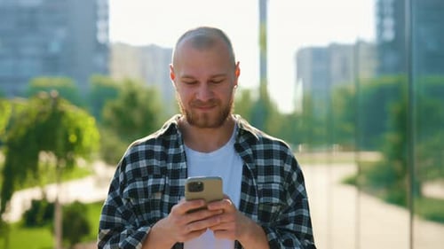 Handsome Young Caucasian Man Using Smartphone Outside Bearded Male Student Texting with Friends