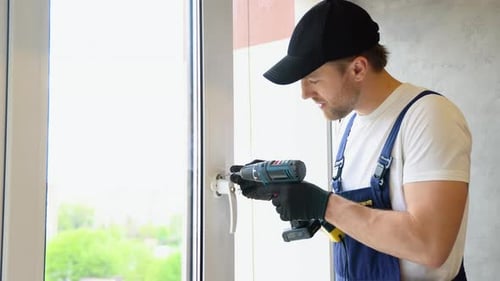 Worker in Overalls Installing a Window Lock for Home Safety The Concept of Protecting a Child From