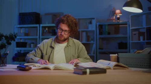 Student Writing Notes While Studying Books at Night