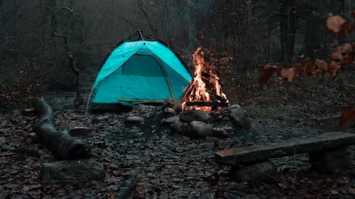 Abgelegener Herbstcampingplatz mit glühendem Zelt und knisterndem Feuer