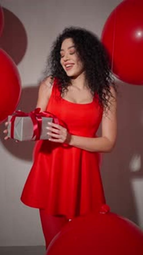 Woman in Red Dress Holds Gift with Red Balls Birthday Celebration Concept