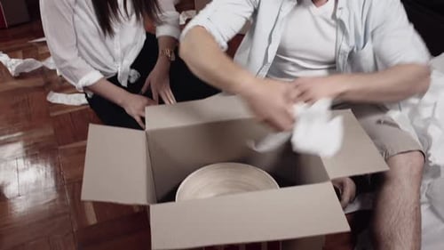 Young Couple Unpacking Bowl from Moving Box Together
