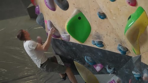 Young Man Climber Training on a Climbing Wall Practicing Rockclimbing View From Above