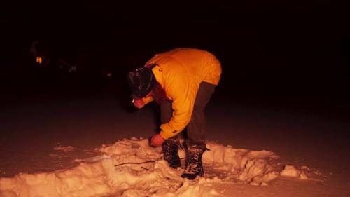 Adult Wearing Yellow Coat Standing in Snow at Night