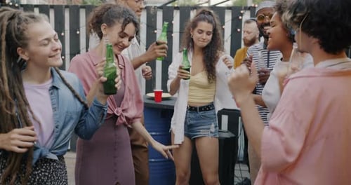 Slow Motion of Happy Young People Dancing to Music at Open Air Cafe Holding Bottles with Drinks